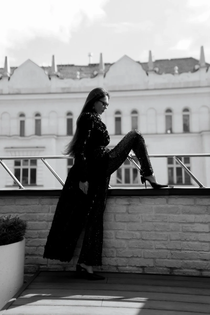 A guest in a long sequinned outfit posing with one foot on the parapet
